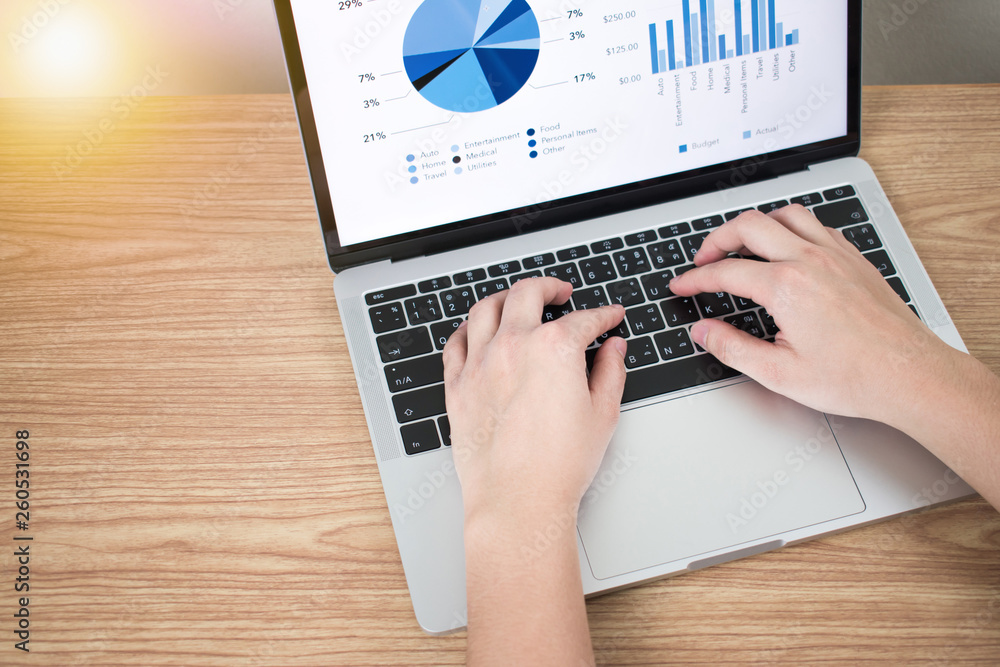 Poster close-up image of the top view of the hand on a laptop showing a financial graph on the screen on a 