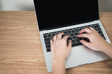 Close-up picture, top view of the hand, people are using a laptop on a brown wood table.