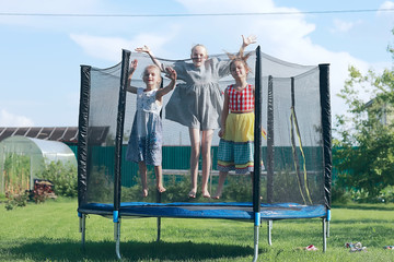 children jumping on a trampoline, girlfriends having fun in the summer in a recreation park on a trampoline