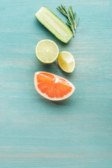 Top view of cut fruits, cucumber and rosemary on blue textured surface