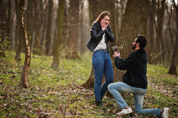 Fototapeta premium Love story of cool multiracial couple in spring forest. Marriage proposal arab man to european girl.
