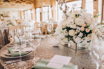 on the banquet table are plates, cutlery, glasses and flower arrangements