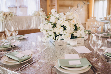 on the banquet table are plates, cutlery, glasses and flower arrangements