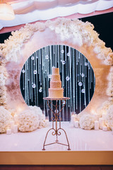 white wedding cake against the backdrop of the ceremonial arch