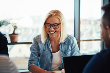 Young businesswoman laughing during a meeting with office collea
