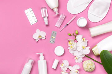 Spa concept cosmetology medicine plastic surgery branding mock-up. White cosmetic bottle gloves slippers hygiene items gasket tampon cotton pads injections tablet orchid on pink background flat lay