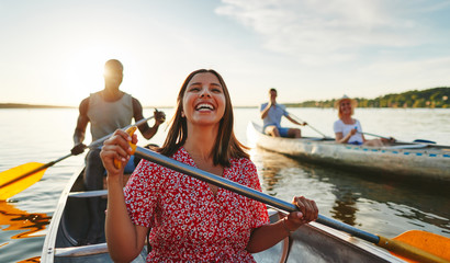 Young woman laughing while canoeing with friends in the summer