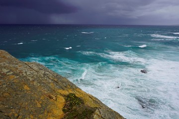 A path on the cliff, storm over the sea , dark sky and large waves, Alentejo, Portugal
