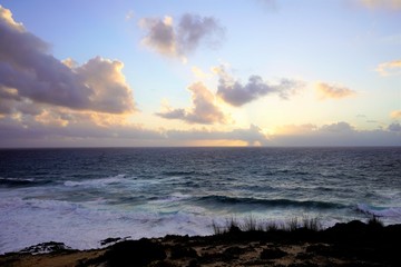 Sunset at the ocean, pink clouds and large waves, Alentejo, Portugal 