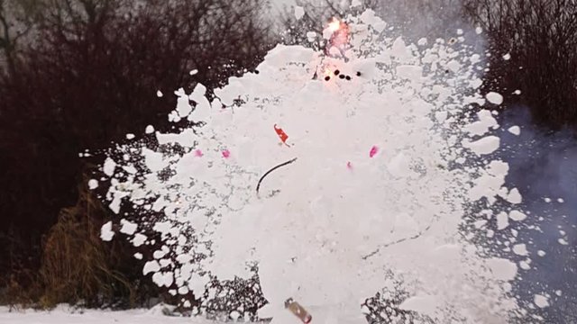 Super slow motion shot of petard explosion inside Snowman head. Fire burst inside top ball and snow fly apart around, destroying one snowball completely. Funny smiling face with pink cheeks