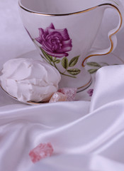 A piece of white marshmallow, which lies on a saucer on the table. Nearby are the sweetmeats