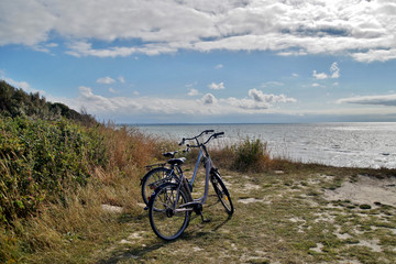 Fototapeta na wymiar view of two bicycles parked and a view of a beach on a sunny Day, Baltic Sea Germany, bicycles on sea cliffs on the Coastal footpath with sky background and sea