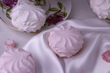 Top view of marshmallows and sweets, which lie on a silk, white cloth