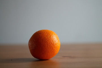 one orange on a wooden table on a light background