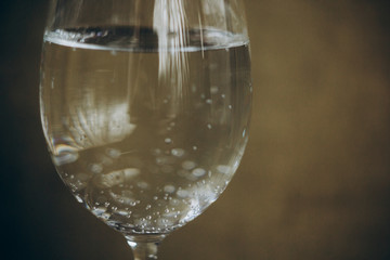 cropped glass of white wine on a rustic wooden brown background. rest, holiday, party. alcoholic drink closeup. copy space