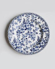 New luxury elegance cutlery view from above on a isolated white background. Top view. Porcelain saucer with blue flowers. Trendy plate. Flat lay view.