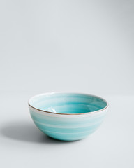 Elegant cutlery on a isolated white background. Front view. Porcelain turquoise blue soup bowl with...