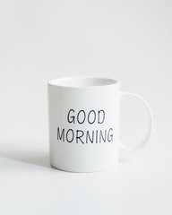 White mug with black inscription good morning. Festive table setting for holiday. On a white background. Front view. Tableware. Isolated.