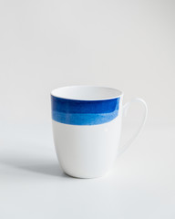 New white mug with blue stripes on isolated background.