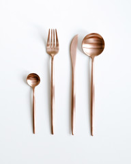 Copper cutlery view from above on a white background. Top view. Knife, tea spoon, fork for a...