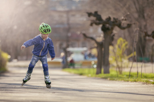 Cute boy in the park rides on the rollers. Sunny and warm.