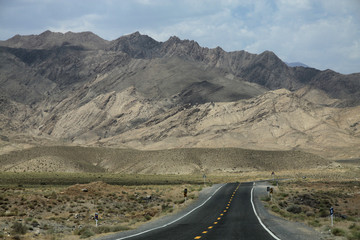 długa prosta asfaltowa droga biegnąca w stronę gór w iranie - obrazy, fototapety, plakaty