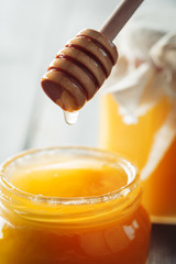 Fototapeta na wymiar Honey background. Sweet honey in glass jar on wooden background.