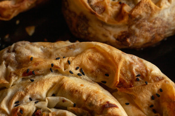 Close up capture of homemade Turkish patty with cheese and meat, black cumin seeds on