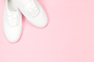 White beautiful women's sneakers on a pink background, copy space, concept shoes