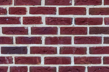 Background image as a fragment of an old red brick wall with traces of erosion (close-up)