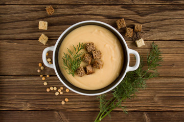 pea soup with croutons and greens on a wooden background