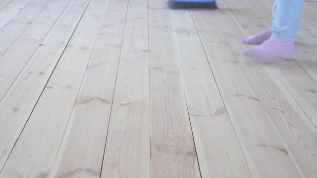 eco-friendly flooring - a woman sweeps a wooden floor