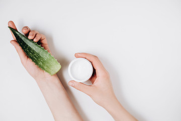 Close up images of female hands and cosmetic cream and Aloe vera fresh leaves on a white background. Organic cream for soft skin. Flat lay, top view, copy space, minimal style. Beauty concept