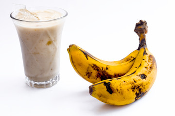 Raw organic fresh banana and its smoothie or shake or banana milk in a glass isolated on white.