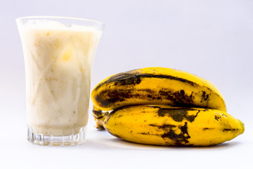 Raw organic fresh banana and its smoothie or shake or banana milk in a glass isolated on white.
