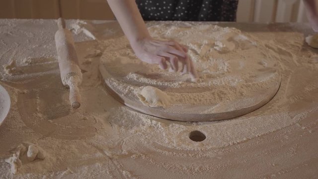 Unrecognized woman in kitchen table draw weave on the board with flour and then blowing white powder