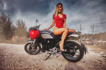 Obraz na płótnie Canvas Outdoor lifestyle portrait of young sexy woman in red swimsuit sitting on a vintage custom motorcycle