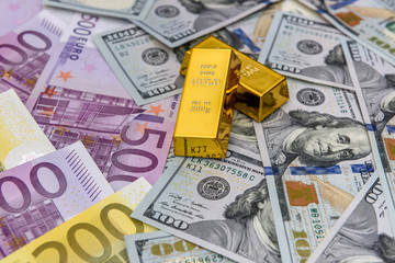 Golden ingot on american dollars and euro banknotes