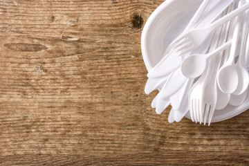 Disposable plastic crockery on wooden background. Top view. Copyspace