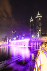 Stunning view of the illuminated Dubai skyline with the magnificent Burj Khalifa in the background and the beautiful and colored waterfalls seen from the Dubai Water Canal boardwalk. Dubai.