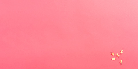 Thumb tacks office supply stationary on a pink paper background