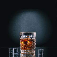 glass of whiskey with ice on black background