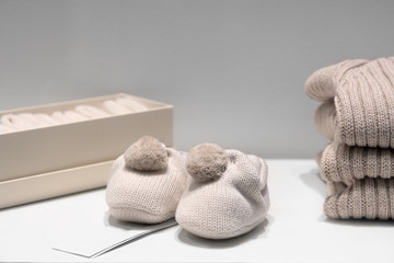 Baby booties, sweaters and socks made of natural beige fabrics lie on the table.