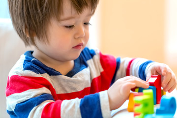 Happy little toddler boy playing with alphabet letters blocks