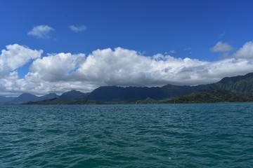 Fototapeta premium Mountains along the Pacific Ocean. Dense jungle growing around and up the steep slopes under a beautiful blue sky