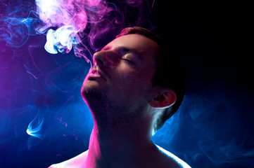 man on a blue background exhales smoke