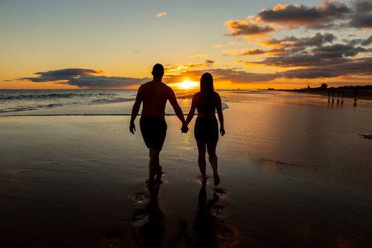 happy couple walking on seashore on a beach vacation or honeymoon trip