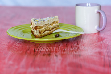 A slice of sponge cake on a plate on a wooden table photographed close up.
