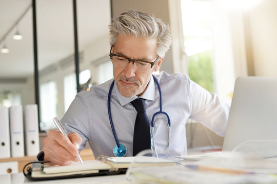 Mature doctor working in contemporary office
