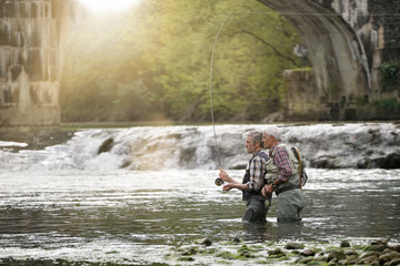 Fly fishing expert guiding novice in river